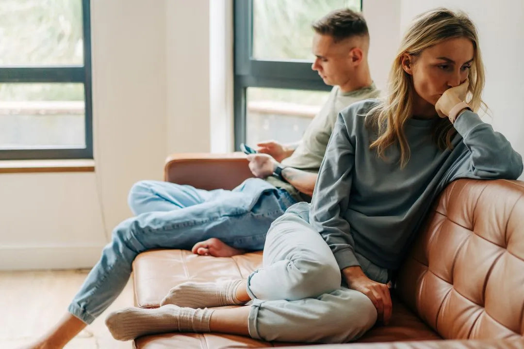 Ein Paar sitzt abgewandt von einander auf der Couch, die Stimmung ist sehr angespannt.