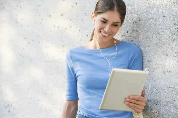 Junge Frau lächelt mit Tablet und Kopfhörern, symbolisiert Kontakt und digitale Angebote des Sera Benia Verlags.