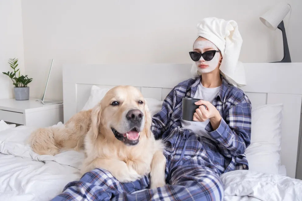 Frau entspannt mit Hund im Bett genießt Selfcare und Me-Time