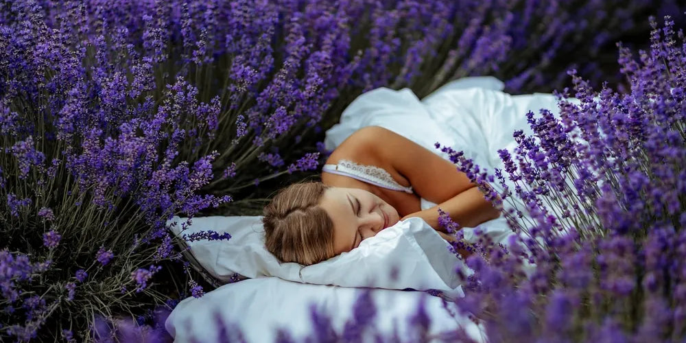 Frau schläft entspannt in Lavendelfeld, symbolisiert Ruhe durch Aromatherapie.