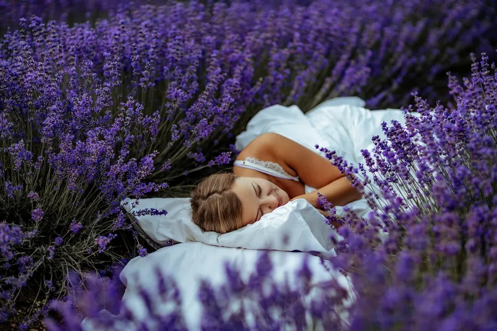 Frau schläft entspannt in Lavendelfeld, symbolisiert Ruhe durch Aromatherapie.