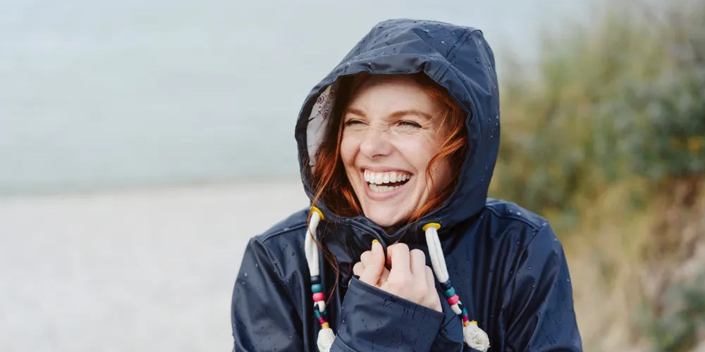 Lachende Frau am Strand symbolisiert Motivation und Lebensfreude, um Ziele zu erreichen.