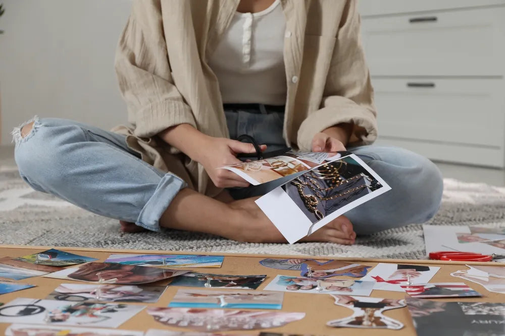 Person schneidet Bilder für Vision Board, symbolisiert Ziele manifestieren und Träume leben.