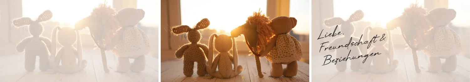 Drei gehäkelte Stofftiere (Hase, Hase, Bär) stehen im Sonnenlicht, symbolisieren Verbundenheit.
