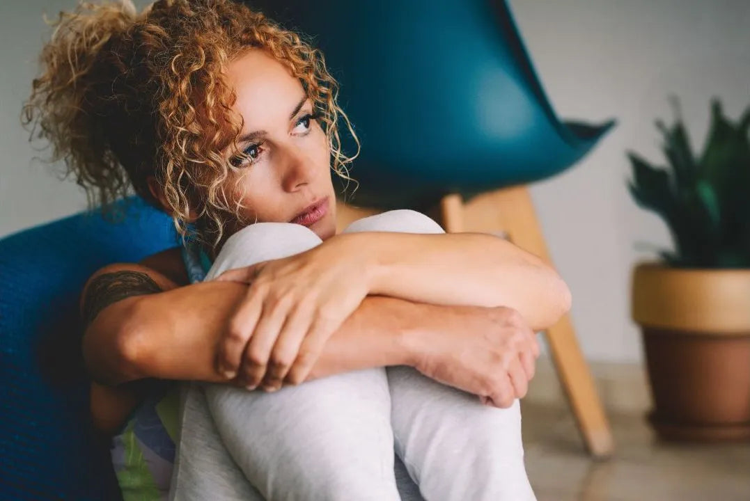 Frau kauert nachdenklich und traurig auf ihrem sofa